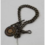 A silver watch chain, with T bar and clip, mounted with a silver and enamel fob, dated 1934