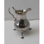 A George III silver cream jug, of baluster form, raised on three trefid feet, hallmarks to base