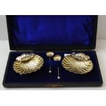 William Devenport, a cased pair of Edwardian silver scallop form salts, with spoons, Birmingham 1905