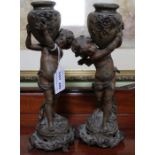 A pair of spelter putti candle holders, 25cm high