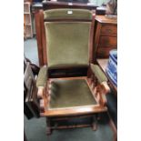 An American show-wood framed rocking armchair with green cord back arm and seat pad
