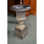 A small black cast iron urn on stand