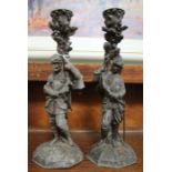A pair of cast metal candlesticks in the form of knights in armour 25cm tall