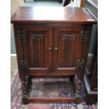 A small reproduction oak side-cabinet with linen fold doors on a baluster turned legs