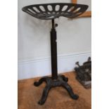 A vintage tractor seat mounted on an adjustable cast base to form a stool