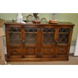 A Reproduction oak finished low part glazed bookcase having four door front and adjustable shelved