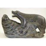 A 20th century Inuit soapstone carving of a polar bear, attacking a walrus, inscribed,