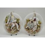 A pair of 20th century Continental porcelain wall plaques, each modelled with a figure in relief, in