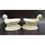 A pair of Royal Worcester bone china, cream glazed salts, in the form of shells supported by merchil