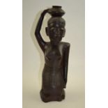 A 20th century African carved wood figure kneeling, balancing a pot on their head, the face with sca