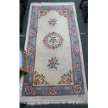 A cream ground rug with floral border and centrepiece