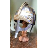 A stainless and brass coloured round knights helmet on stand