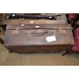 A large vintage leather suitcase with travel labels
