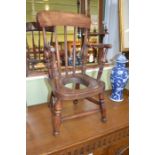 A provincial child's open arm stick back potty chair, elm seat, Windsor type, raised on turned suppo