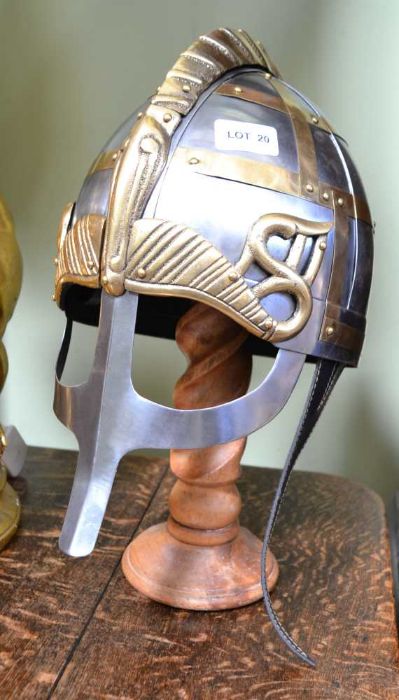 A stainless and brass coloured round knights helmet on stand