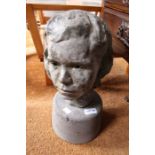 A cast example of a girls head sat on a concrete base