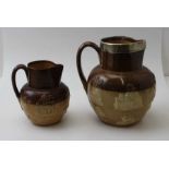 Two Royal Doulton stoneware jugs, with applied decoration, the largest with silver rim
