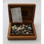 A thuja burr aromatic wood box containing ovoid stone samples to include; rose quartz, jade stone, e