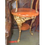 A gold painted cast Britannia three legged pub table having circular wooden top and under tier