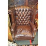 A reproduction Georgian design wingback armchair upholstered in distressed chocolate brown