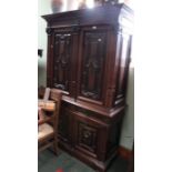 A Continental carved oak cabinet, with decorative panel cupboard doors over a base section with two