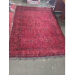 A well woven pigeon red woollen floor carpet, the central field having eight floral motifs within mu