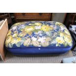 A large over stuffed tapestry topped foot stool on turned legs and castors