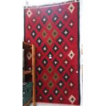 A hand woven Kelim with red ground and lozenge decoration 160 x 90 cm