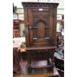 A reproduction carved oak single door cupboard on turned supports