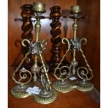 A pair of ornate brass candlesticks with a pair of barley twist wooden examples