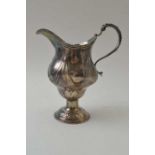 A Georgian silver milk jug of baluster form raised upon a dome foot, embossed swag decoration, weigh