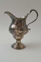 A Georgian silver milk jug of baluster form raised upon a dome foot, embossed swag decoration, weigh