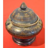 A South-East Asian pottery lidded bowl 12 cm high on a turned wood stand, mottled brown glaze