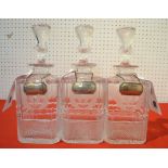 A suite of three heavy cut-glass sprit decanters with thistle stoppers and each with a silver label