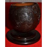 A 19th century coconut cup carved with trophies of music and war on a -platform base 10 cm high