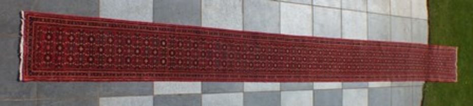A Persian Hosseinabad runner, red ground, geometric design, fringed and bordered, 772cm x 70cm