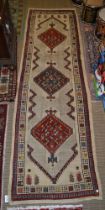 A Persian runner, cream ground with three lozenge patterns in red, blue and green, fringed and