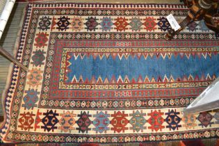 An antique Kazak long rug, having narrow plain central blue panel,