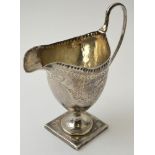 An 18th century silver pedestal cream jug, with bright cut swag decoration, having oval blind cartou