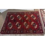 A red ground Turkoman rug, styled motifs in cream and blue, fringed 178cm x 127cm