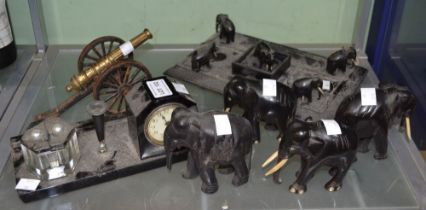 Two vintage ink stands, a selection of black carved elephants & a desk cannon