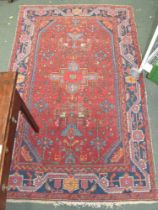 An Eastern wool rug, crimson ground, deeply blue bordered, 218cm x 130cm