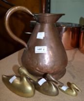 A copper jug and a trio of brass ducks
