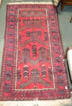 An Eastern wool crimson ground tribal design rug, fringed & bordered, 200cm x 104cm