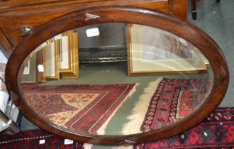 An oval oak framed bevel edged wall mirror