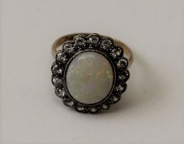 A 9ct gold ring, set an oval opal surrounded by a frame of seventeen gemstones, ring size K