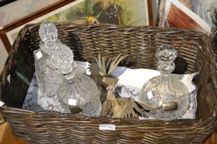 A basket with three decanters and labels and a pair of cast metal fighting cocks