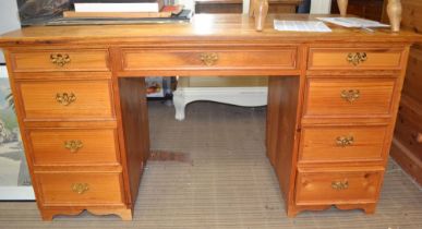 A modern pine one piece twin pedestal desk of nine drawers
