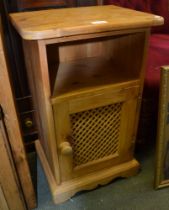 A modern pine bedside unit with lattice panelled door