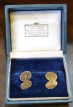 A pair of yellow metal oval cufflinks, with engraved floral sprays, cased